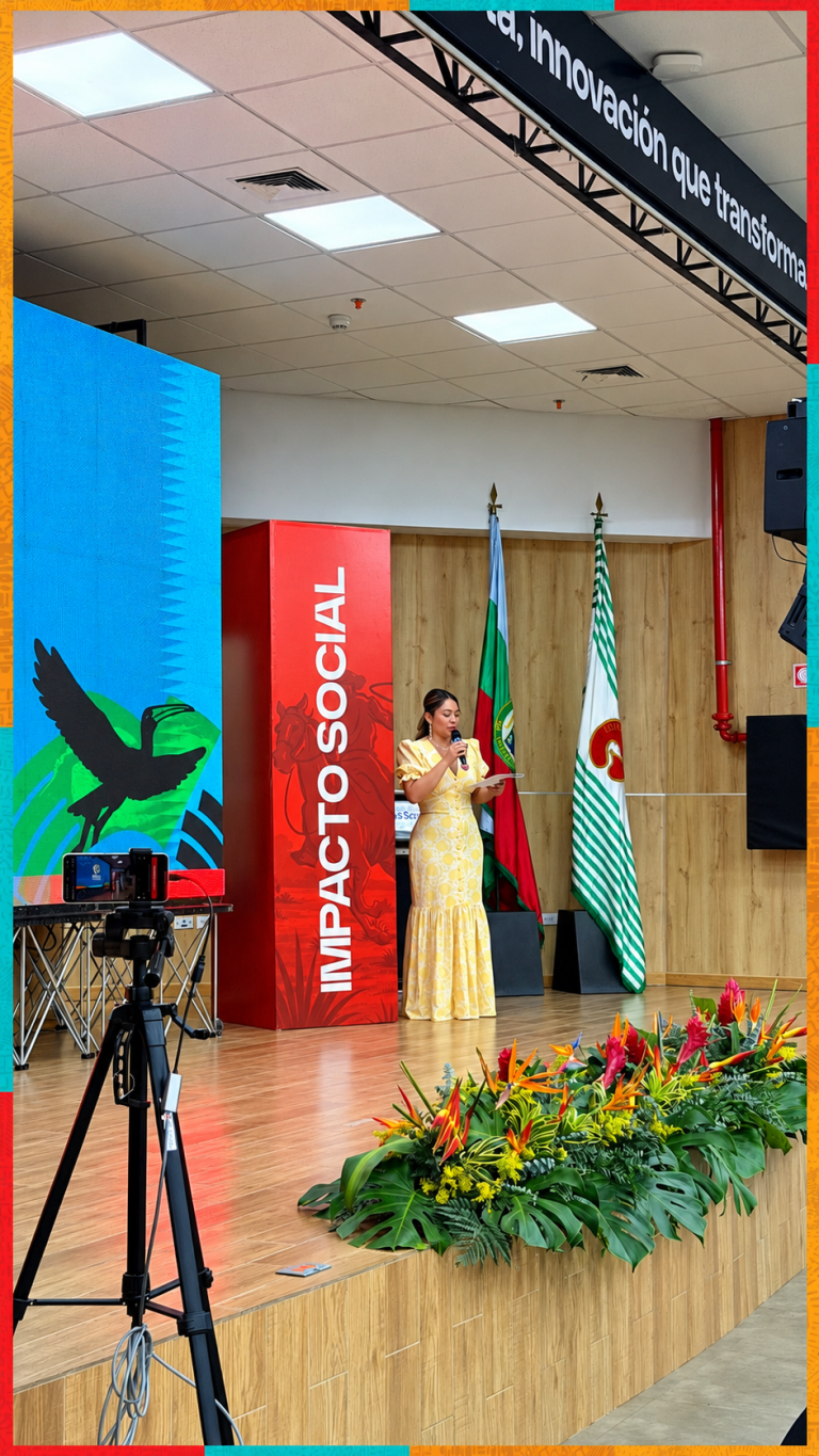 Oradora en escenario con flores y banderas
